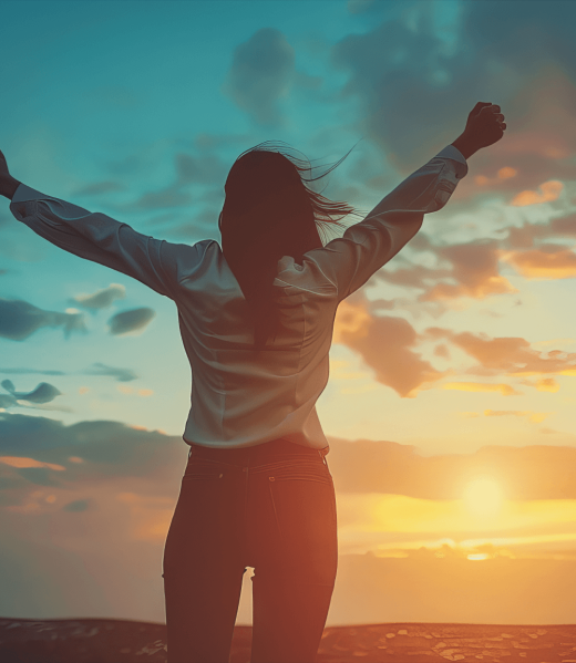 about-us-1 woman raising hands in success in front of a sunset